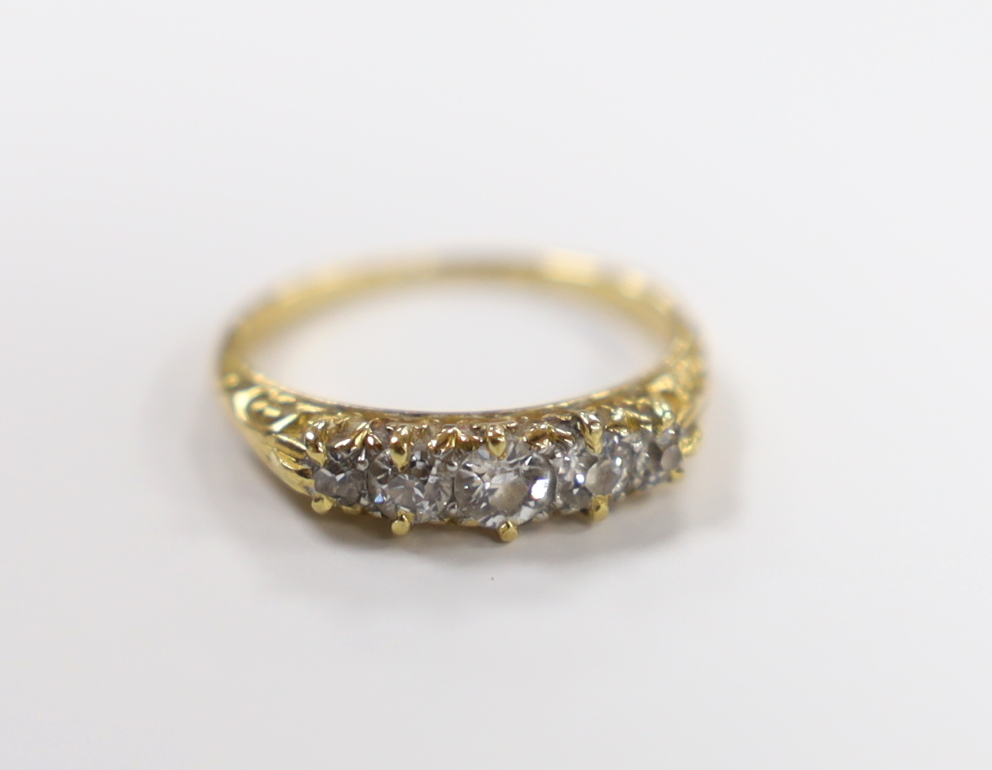 An early 20th century yellow metal and graduated five stone diamond set half hoop ring, size I, gross weight 2.1 grams.